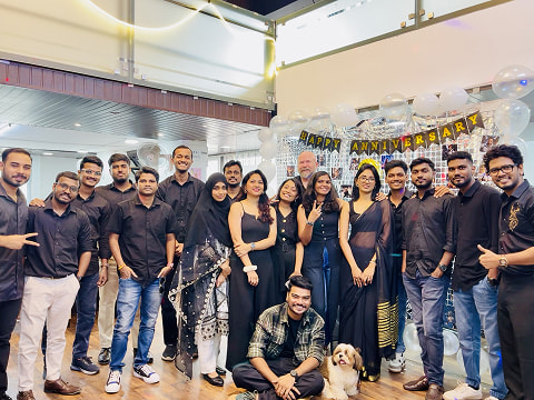 ImmensoTech software development team celebrating company anniversary in black themed outfits at the office